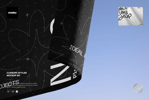 Detailed closeup of a fabric flag mockup with white lettering and shapes, corner edge visible, sky in the background.