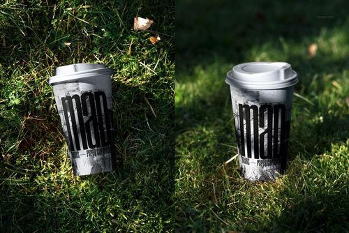PSD mockup of a paper cup with a lid and bold graphic print, shown outdoors on grassy ground with shadows.