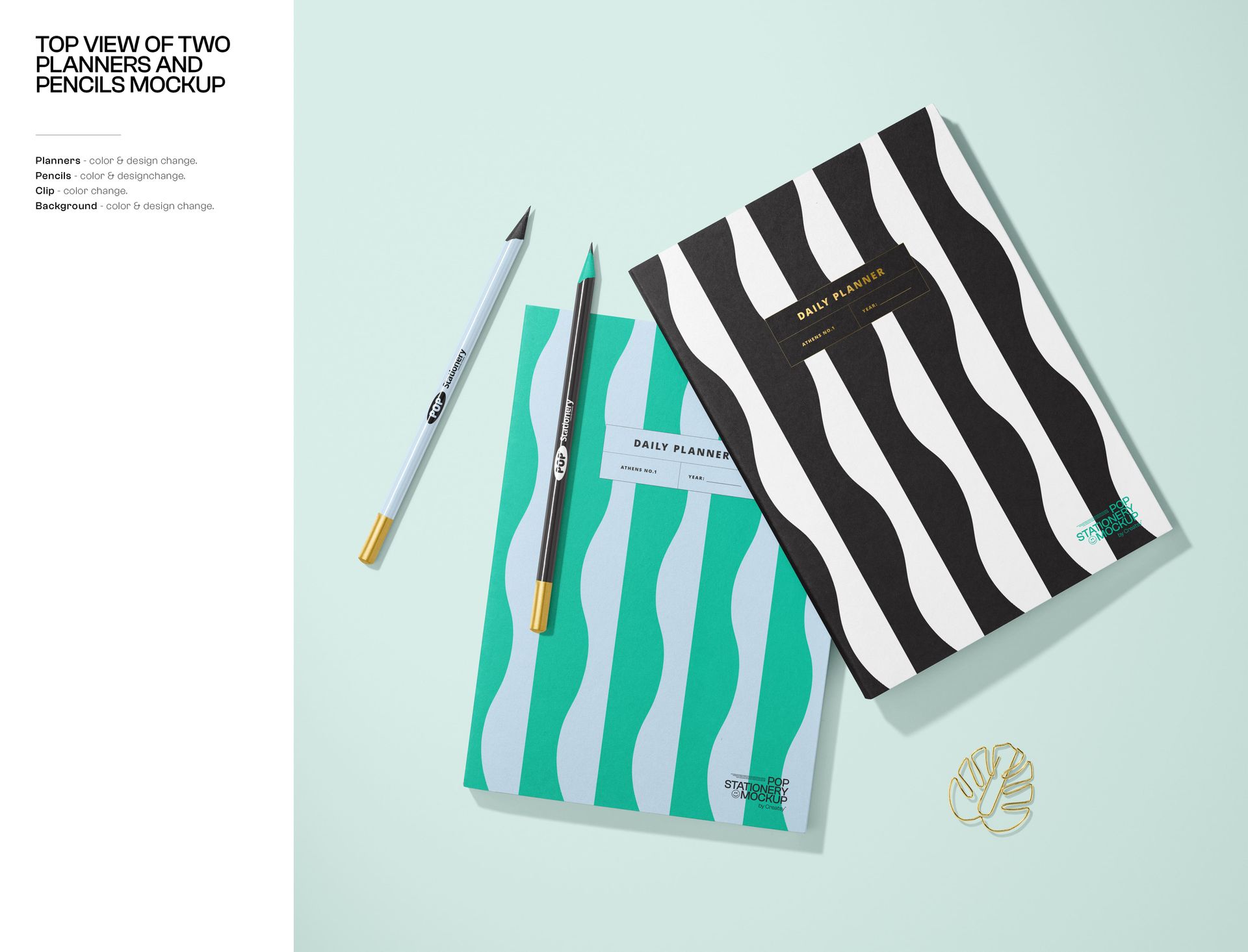 Stationery mockup showing two notebooks with graphic covers, pencils, and a gold leaf-shaped paper clip from above.