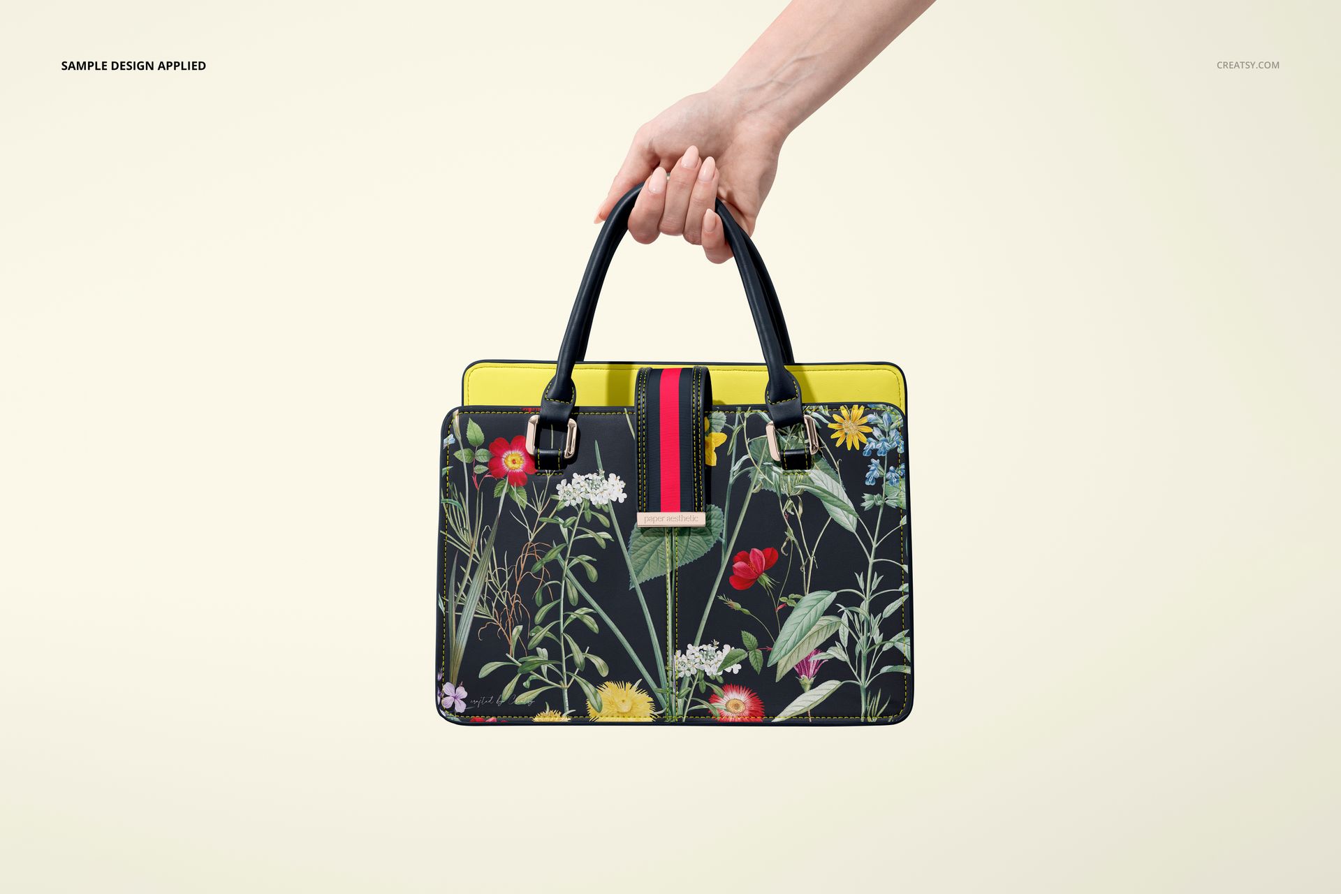 Leather handbag mockup with black handles, vivid flower design on the front, and yellow trim, shown against a light background.