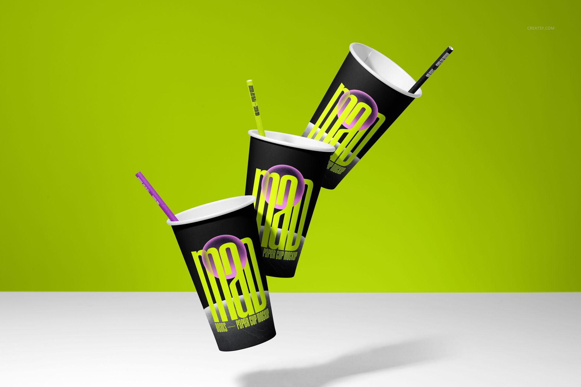 PSD mockup featuring three stylish paper cups with bright graphic designs and straws, set against a green backdrop.
