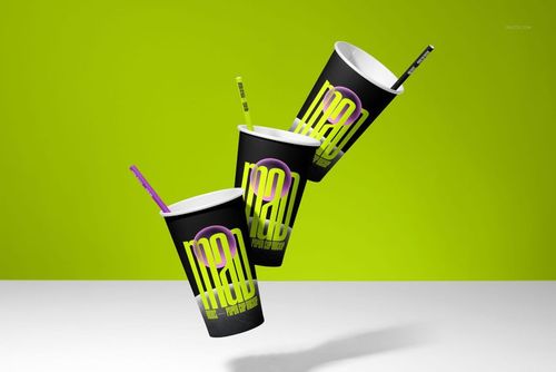 PSD mockup featuring three stylish paper cups with bright graphic designs and straws, set against a green backdrop.