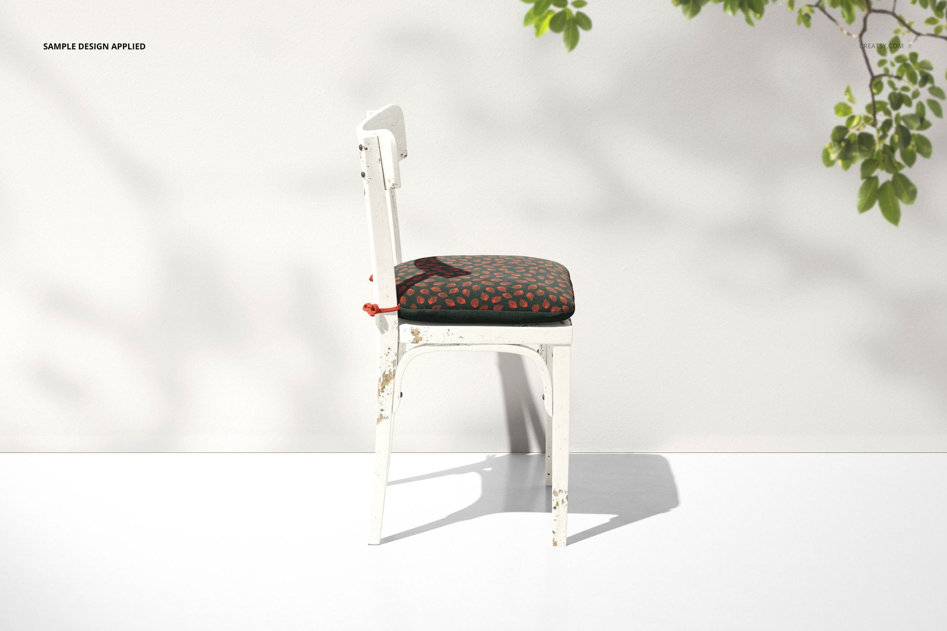 Rustic chair cushion mockup featuring a distressed white chair and a dark cushion with a subtle red pattern, side perspective.