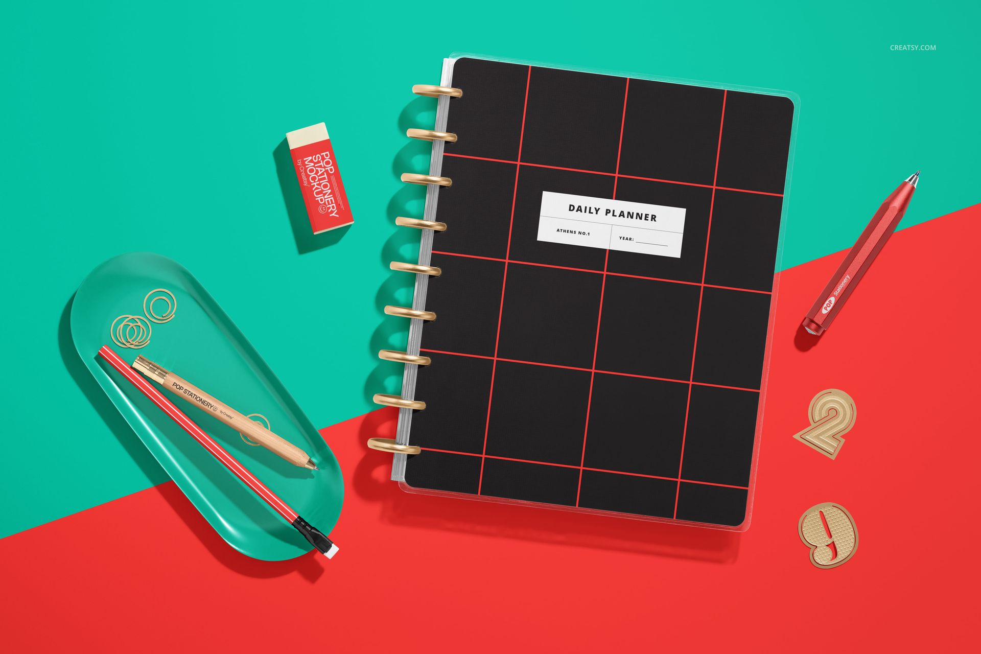Top view of a spiral planner mockup with dividers, black cover featuring red grid lines, and desk accessories.