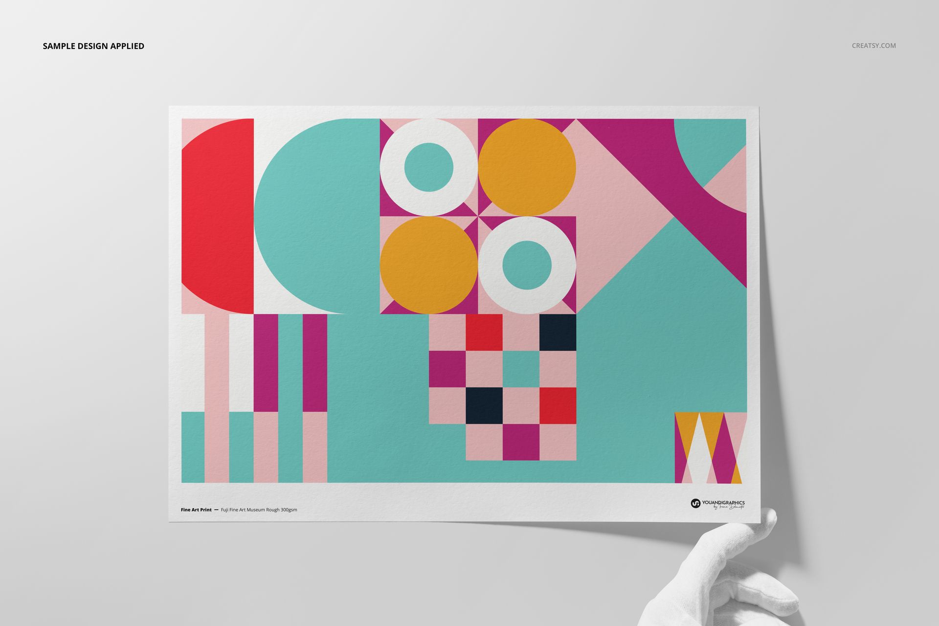 A3 fine art print mockup featuring geometric abstract shapes in pink, yellow, turquoise, and white, held by a gloved hand.