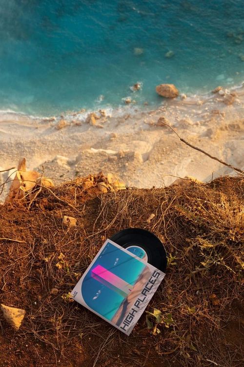 7 inch black vinyl record mockup set on earthy terrain at the edge of a cliff with the sea visible below.