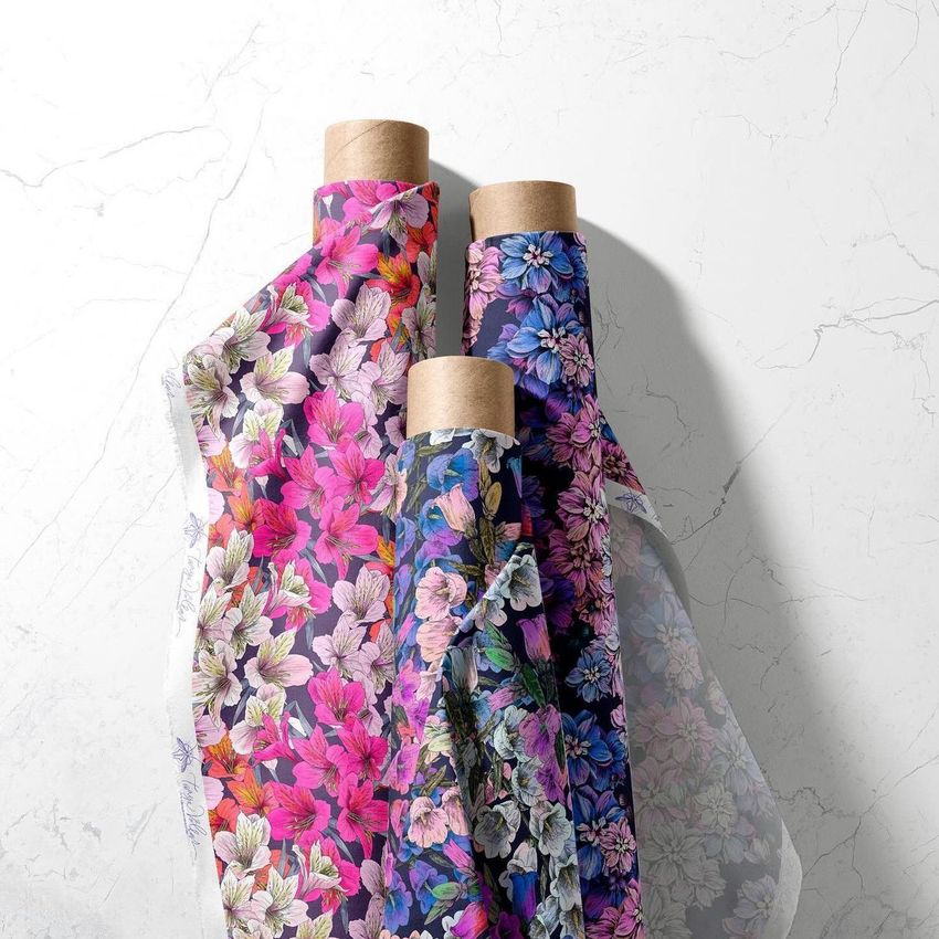 Three fabric rolls mockup with floral patterns in pink, purple, and blue tones, displayed on a light marble surface.