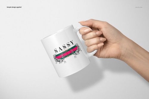 Hand holding a white 11oz mug with a colorful horizontal stripe and decorative text design, front view on light background.