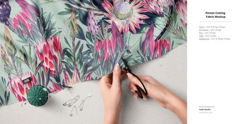 Fabric mockup showing hands trimming botanical textile design, with green pincushion and scattered pins in view.