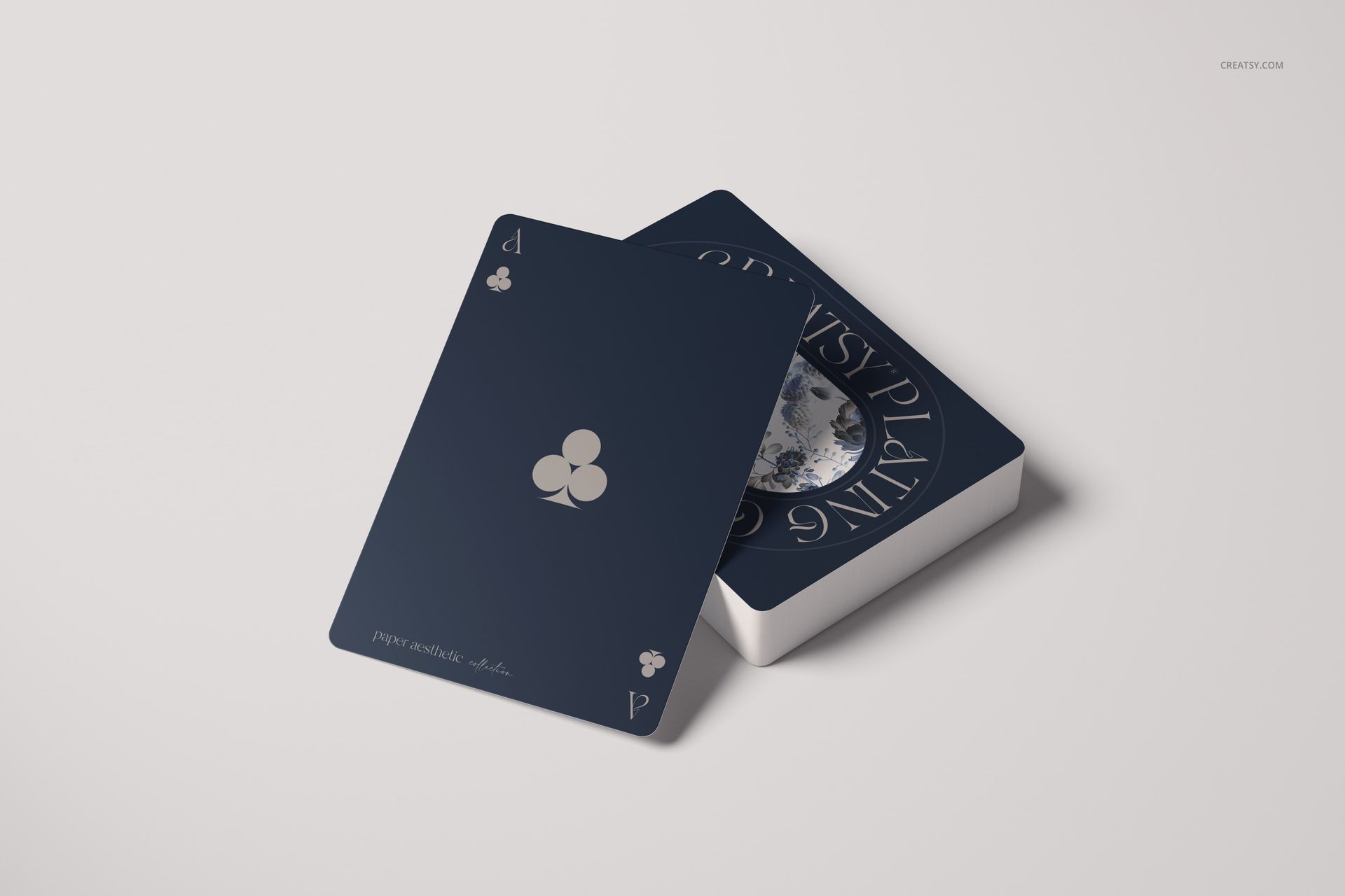 Two playing cards with a dark blue design, one showing the ace of clubs, displayed on a light background in a mockup scene.