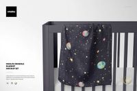 Space-patterned muslin swaddle blanket mockup hanging on the side rail of a modern gray crib against a plain background.