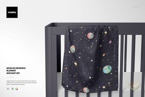 Space-patterned muslin swaddle blanket mockup hanging on the side rail of a modern gray crib against a plain background.