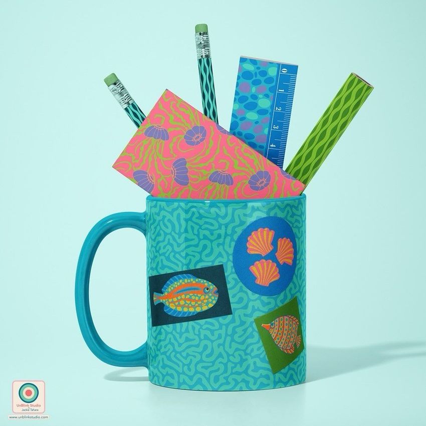 Mug mockup with a blue and green aquatic pattern, holding pencils, a ruler, and colorful stationery on a light blue background.