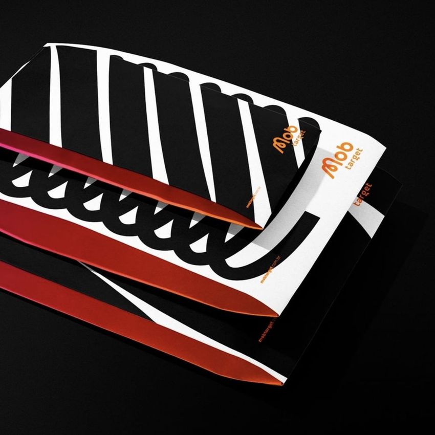 Three kraft mailer mockups with bold black and white diagonal stripes and orange accents arranged on a dark surface.