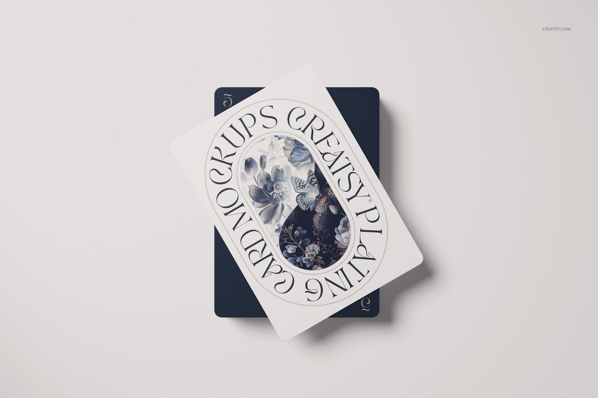 Playing cards mockup showing a card with ornate floral pattern and circular text overlay, placed on another dark card.