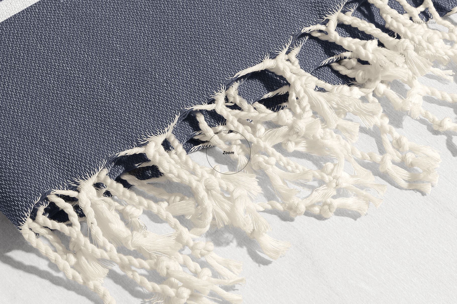 Detailed shot of a Turkish towel mockup showing textured dark blue material and decorative white tassel fringe.