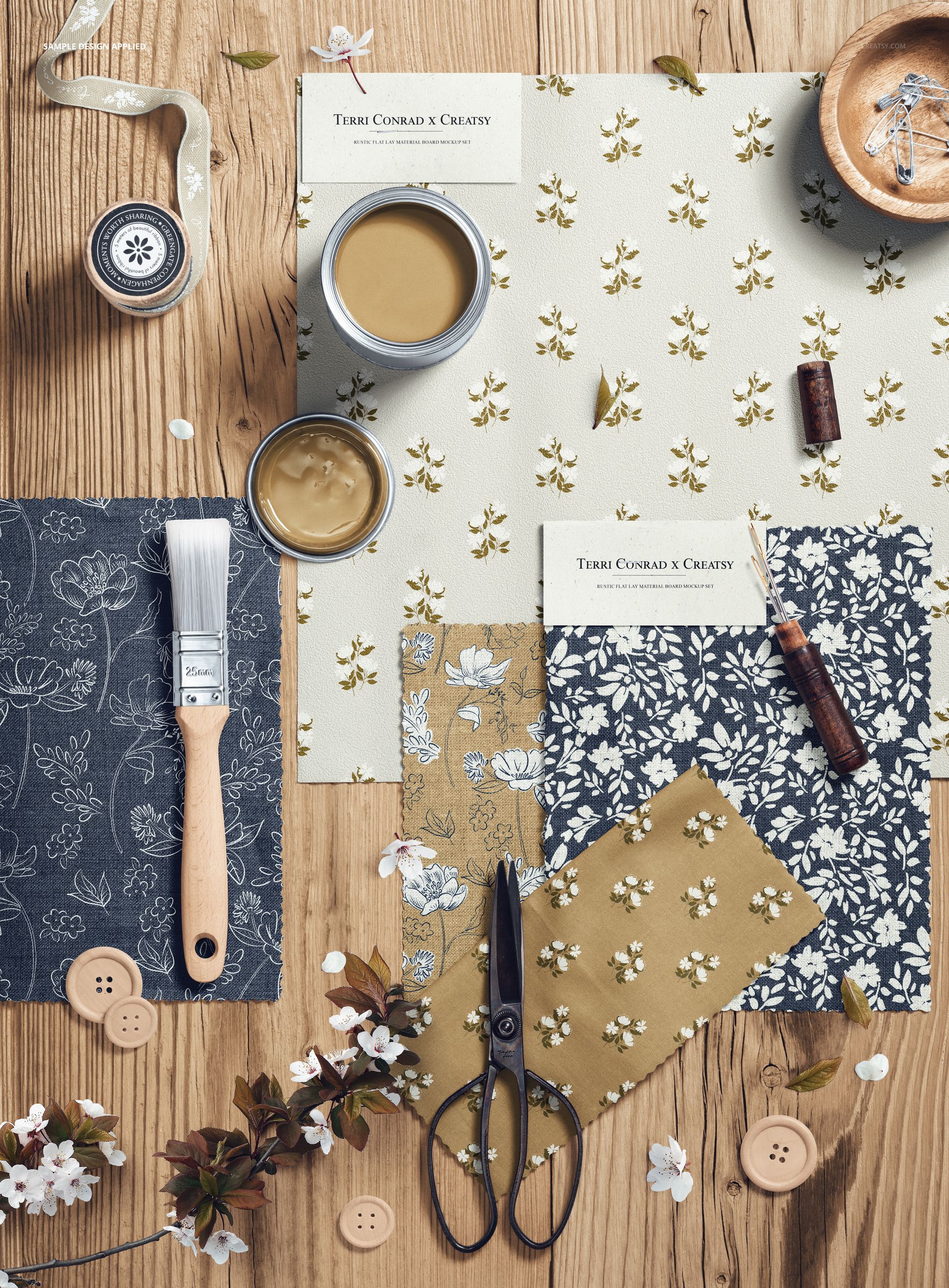 Top view of a rustic flat lay fabric moodboard mockup with floral patterned textiles, scissors, buttons, and paint jars on wood.