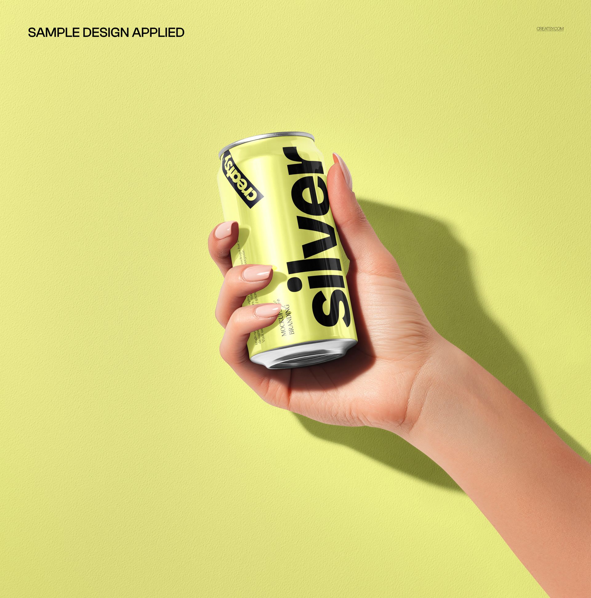 PSD mockup featuring a person’s hand holding a yellow drink can labeled silver, with a soft yellow backdrop.