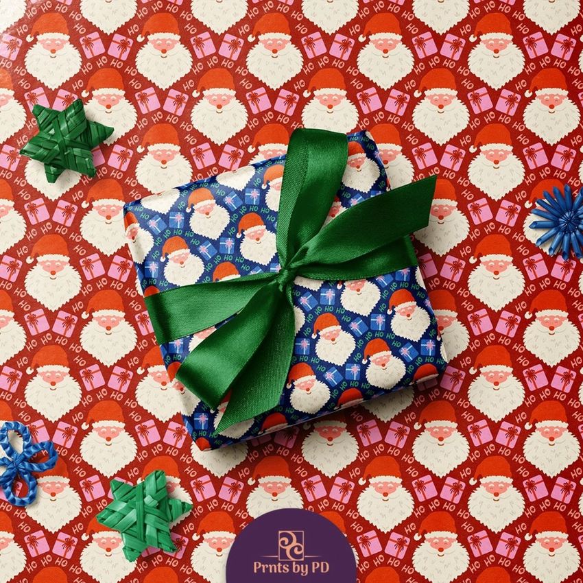 Square gift box mockup wrapped in blue paper with Santa faces and green ribbon, placed on red festive wrapping paper.