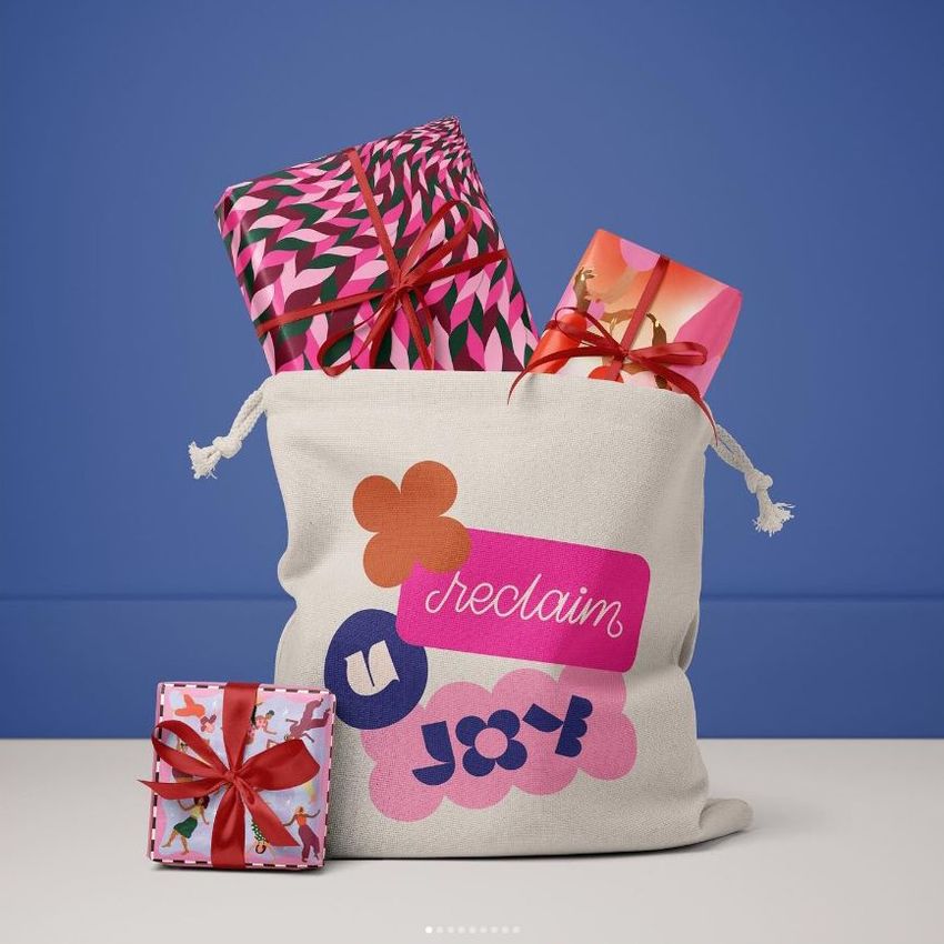 Santa bag mockup with colorful geometric and floral patterns, filled with wrapped presents and set against a blue background.