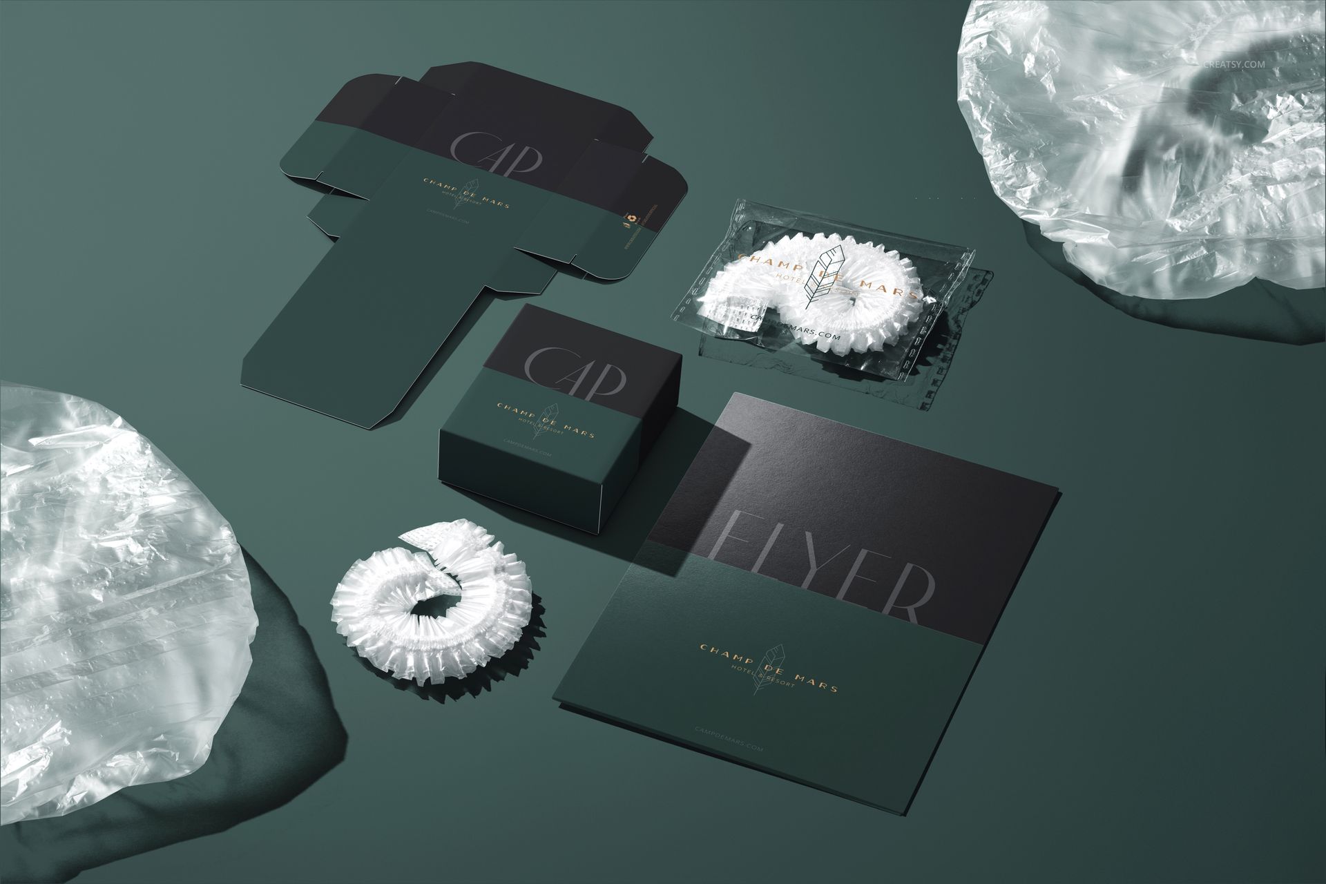 Hotel shower cap mockup featuring a folded shower cap, packaging box, unfolded box template, and printed flyer on a green surface.