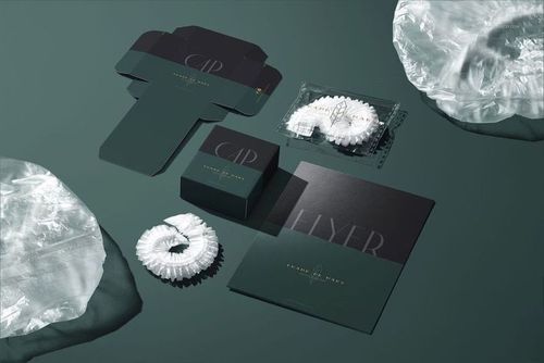 Hotel shower cap mockup featuring a folded shower cap, packaging box, unfolded box template, and printed flyer on a green surface.