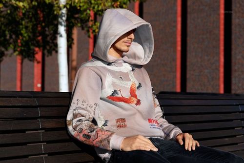 PSD mockup of an oversized hoodie with detailed bird and scenic design, displayed in an outdoor urban setting.