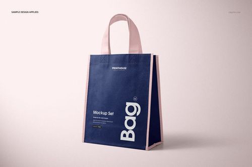 Front angled view of a non-woven tote bag mockup with navy blue body and pale pink handles against a light background.