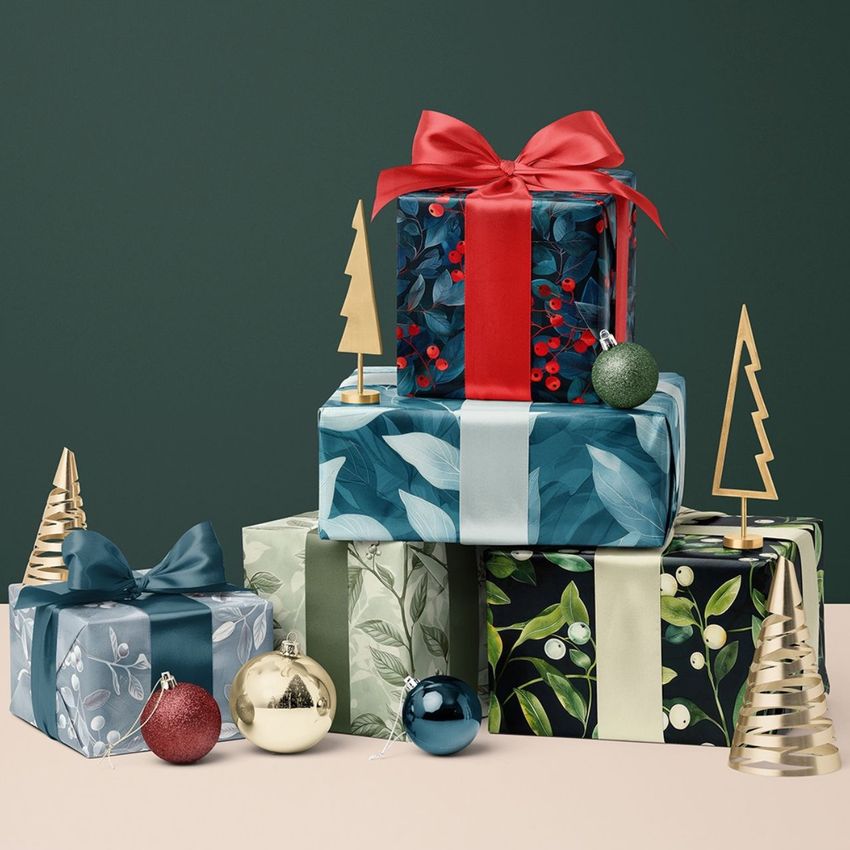 Christmas gifts mockup featuring a pile of wrapped presents with botanical patterns, satin ribbons, and festive ornaments.