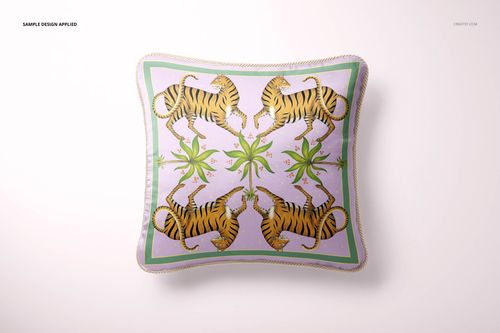 Silk pillow mockup with braided trim, decorated with mirrored tiger motifs and green plants, viewed from above.