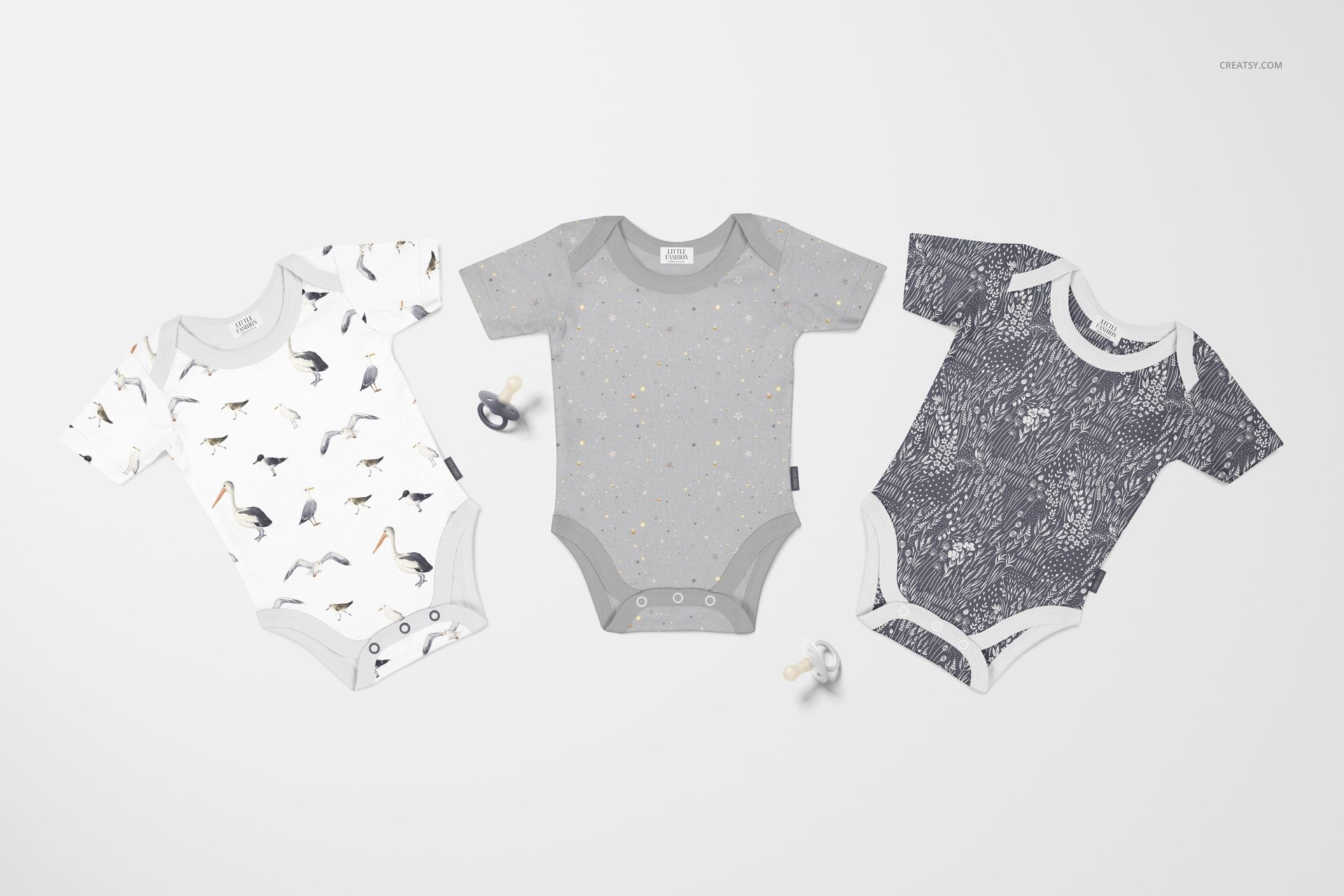 Top view of three patterned baby onesies, including animal and abstract designs, laid out side by side as a mockup.