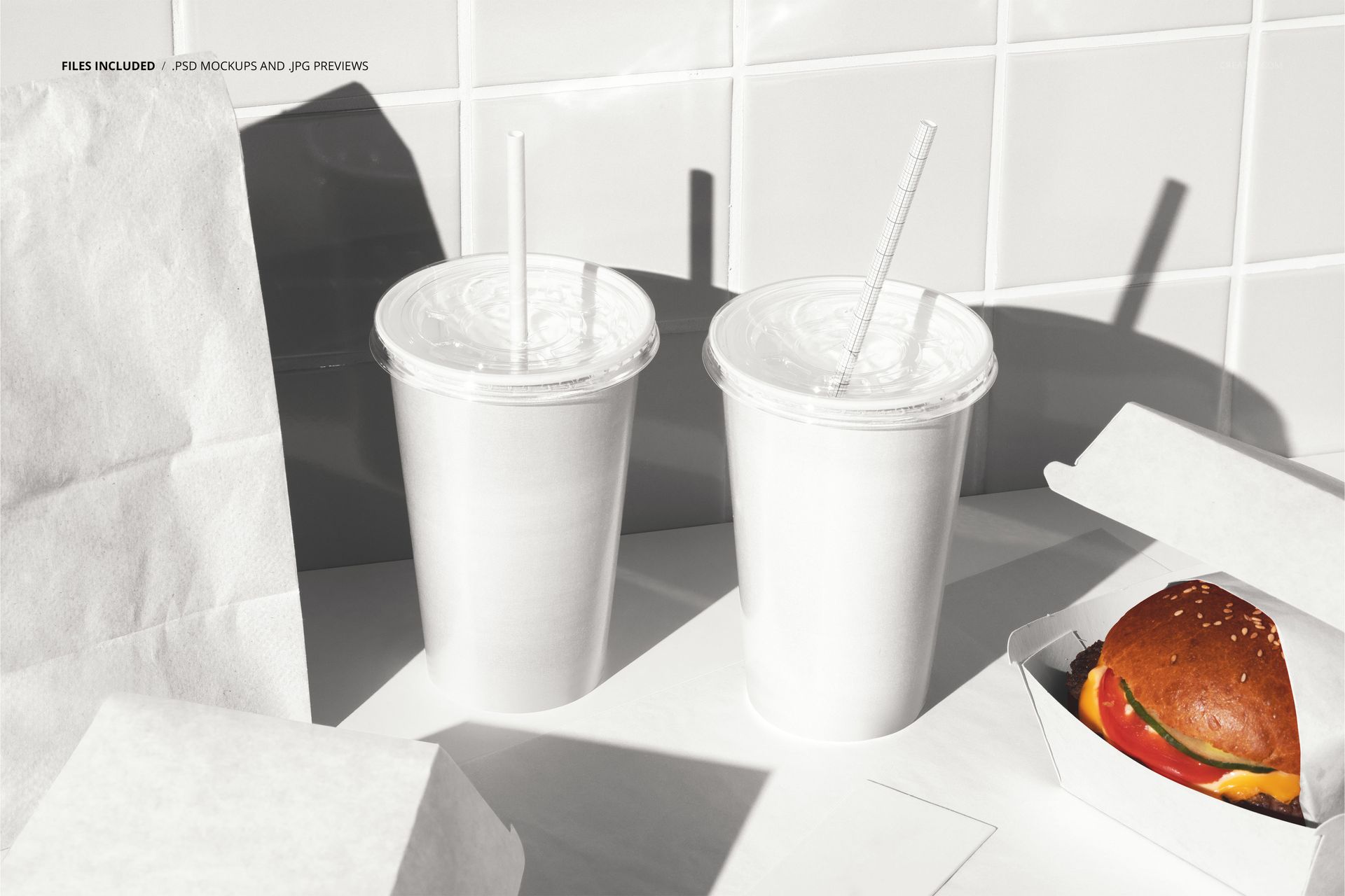 Front view of burger packaging mockup with white paper bag, two blank cups with straws, and open burger box on a tiled surface.