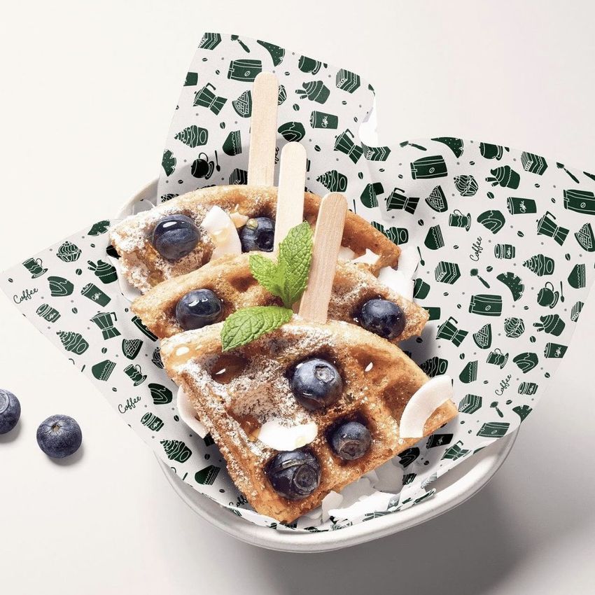 Food safe paper mockup featuring a bowl with three waffle pieces topped with blueberries, coconut flakes, and mint leaves.