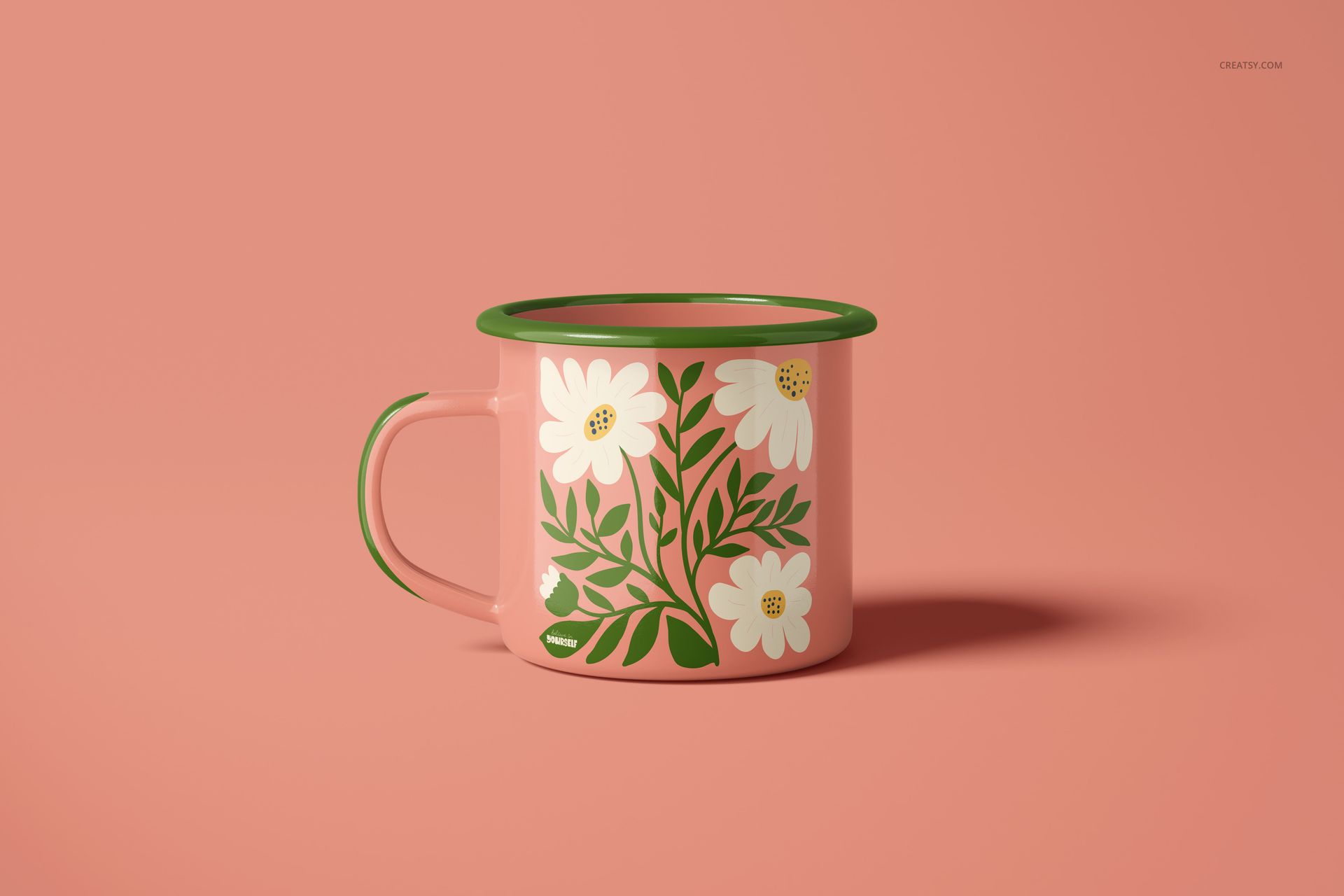 PSD mockup of a pink enamel mug with a green rim and handle, adorned with white floral motifs, set against a pink backdrop.