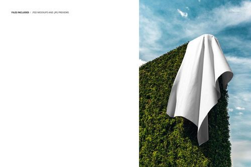 Plain white textile mockup displayed on a neatly trimmed hedge outdoors, with sky and clouds above, seen from the side.