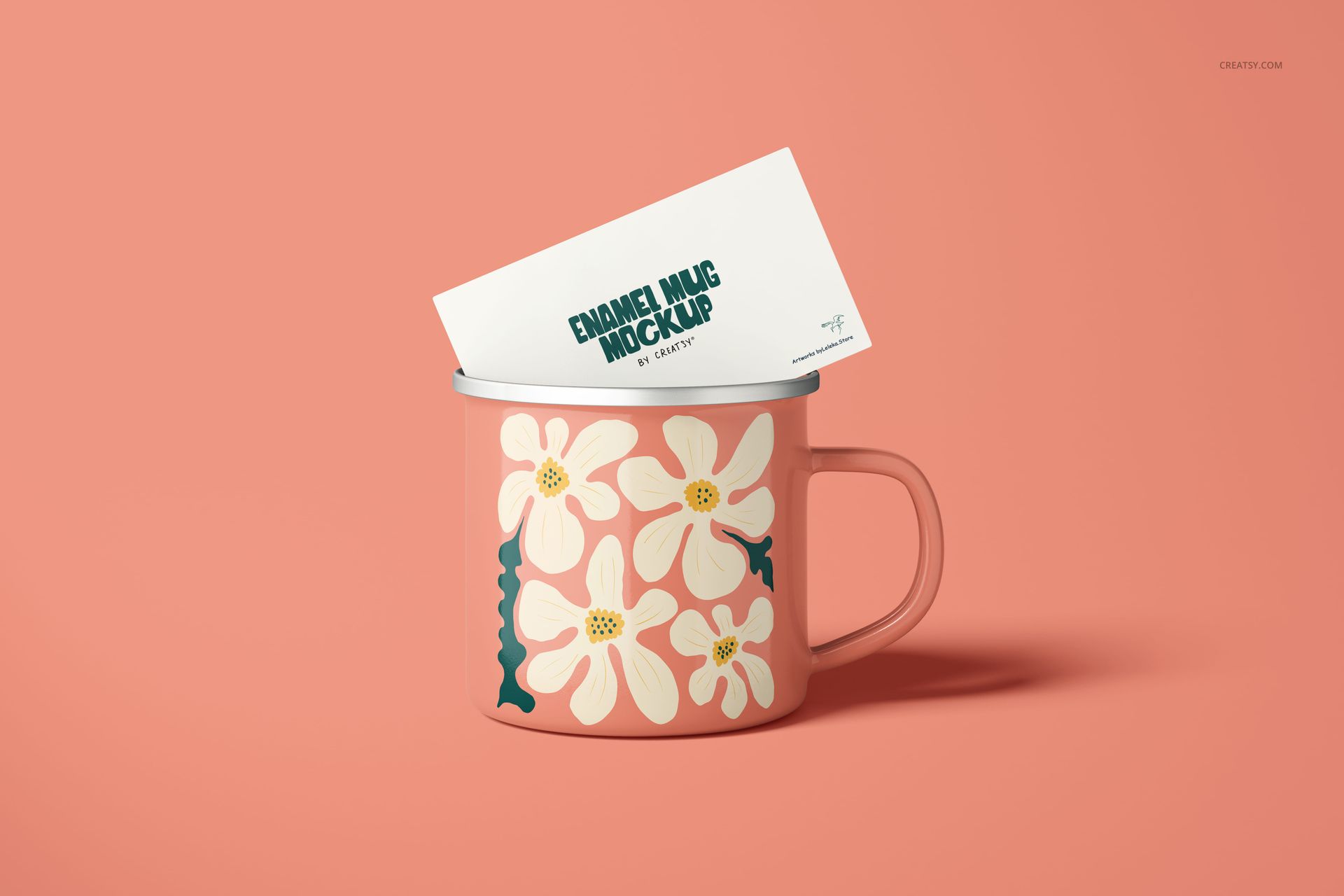PSD mockup of a floral enamel mug with a silver rim, shown from the front with a card inserted, against a peach backdrop.
