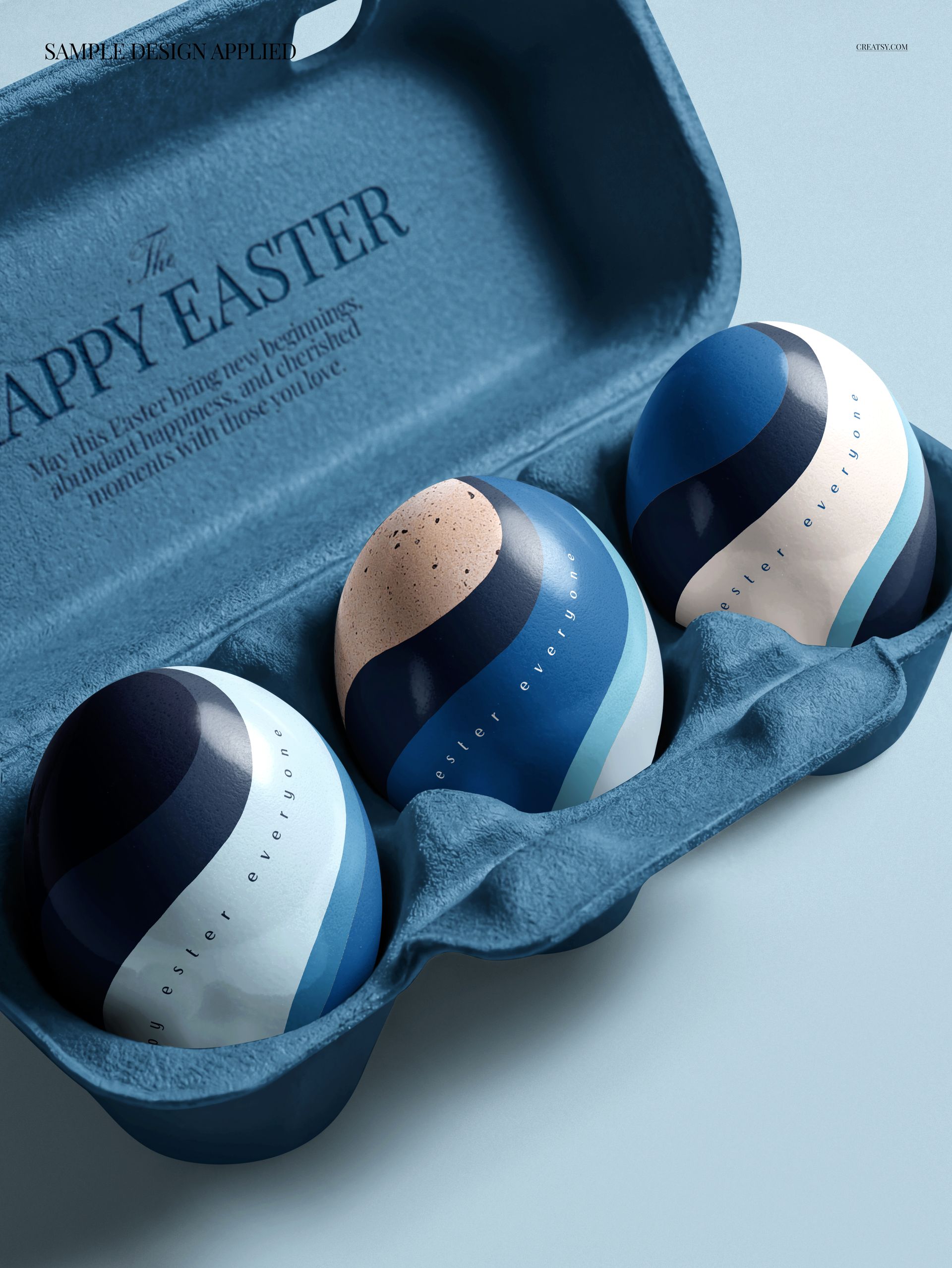 Three Easter eggs with abstract blue and white patterns placed in a blue carton, front view mockup scene.