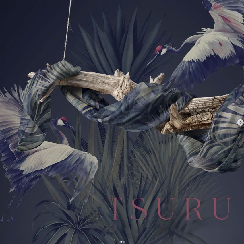 Fashion accessory mockup showing a patterned silk scarf wrapped around driftwood with cranes and palm leaves in the scene.