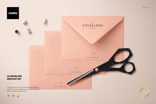 C6 envelope PSD mockup featuring a trio of peach envelopes, gold details, scissors, and pen caps on a neutral background.