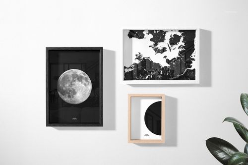 Minimalist scene featuring three wooden picture frames mockup with abstract and moon-themed black and white designs.