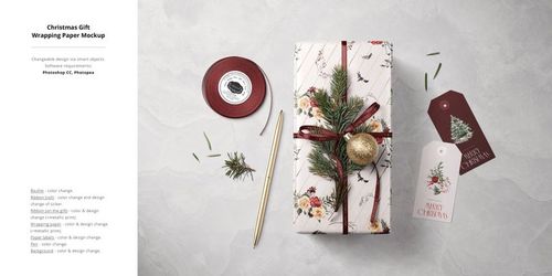 Holiday mockup featuring a wrapped gift, pine sprig, gold bauble, ribbon roll, and Christmas-themed gift tags.