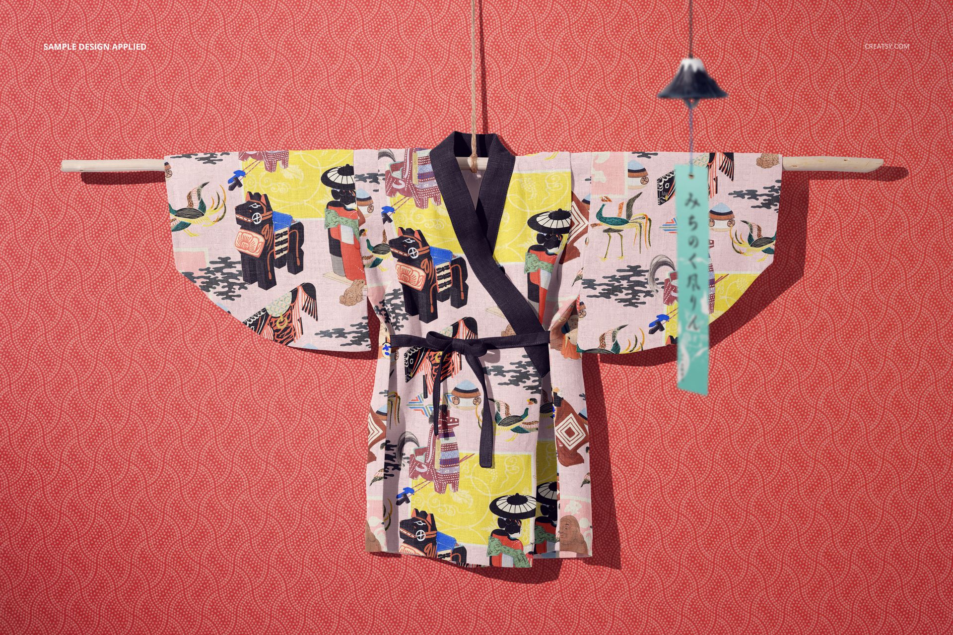 Front-facing kids yukata mockup featuring vibrant graphics and dark trim, hung on a rod with a red patterned backdrop.
