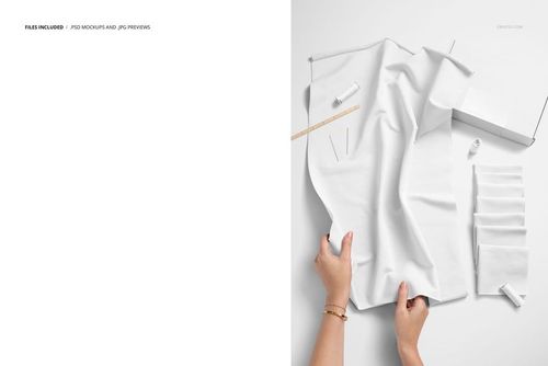 Flat lay of white jersey fabric mockup with sewing accessories, including a box, ruler, needles, and thread on a white surface.