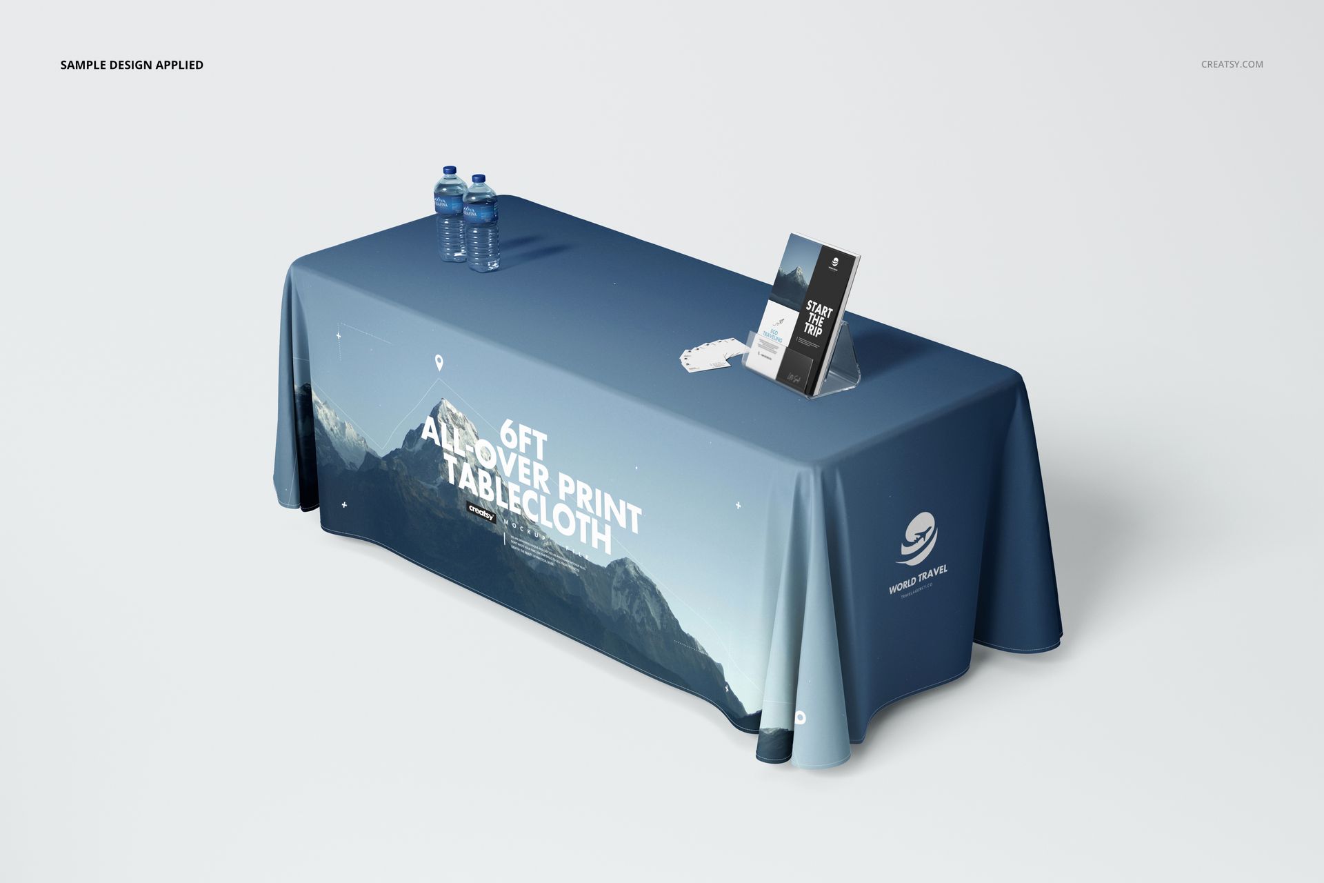 6ft printed polyester tablecloth mockup with blue gradient and mountain graphics, displayed on a table with props in a studio setting.