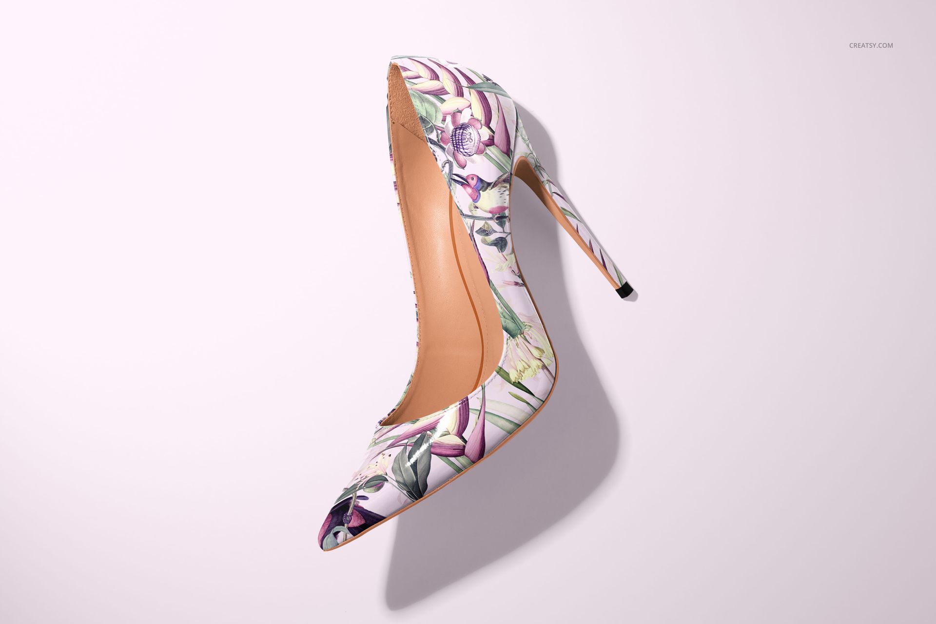 PSD mockup of a pointed high heel shoe with multicolored floral design, isolated on a soft pink surface.