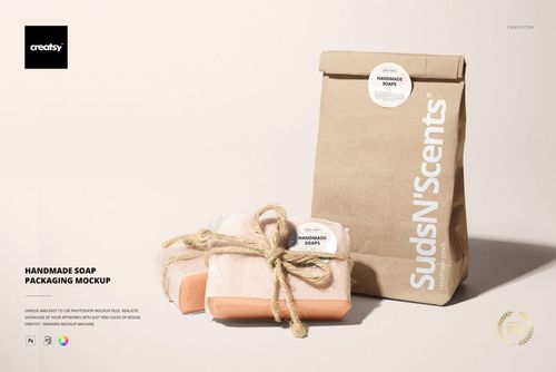 Handmade soap packaging mockup showing two wrapped soap bars with twine and a brown paper bag on a light background.