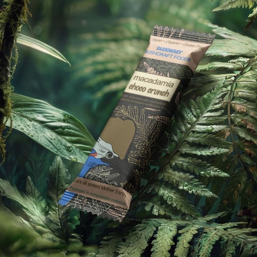 Candy bar mockup featuring illustrated packaging with a cassowary bird, placed among lush green jungle leaves in natural light.