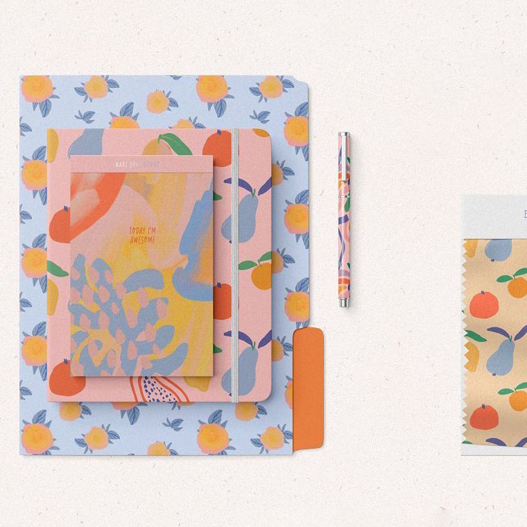 Stationery set mockup featuring patterned notebooks, a pen, and a folder arranged on a light textured surface.