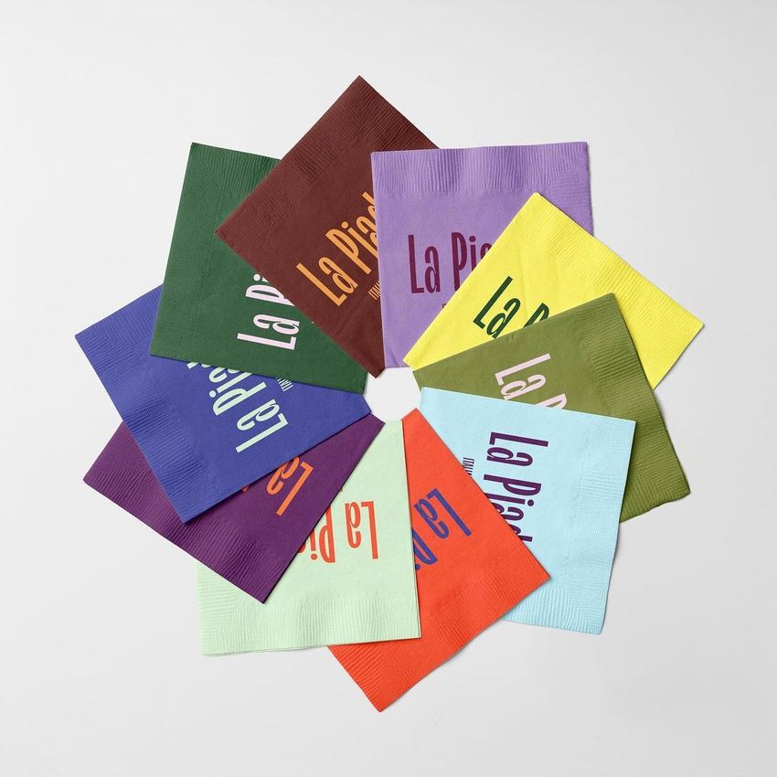 Paper napkins mockup featuring nine colorful napkins arranged in a circular pattern on a light gray surface.