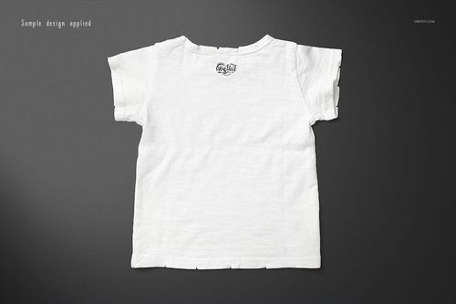 White kids t-shirt mockup displayed from the back on a dark surface, featuring a small graphic at the neckline.